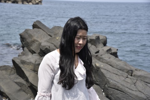 Mr. Ugyen Doji's sister is standing on a rock by the sea