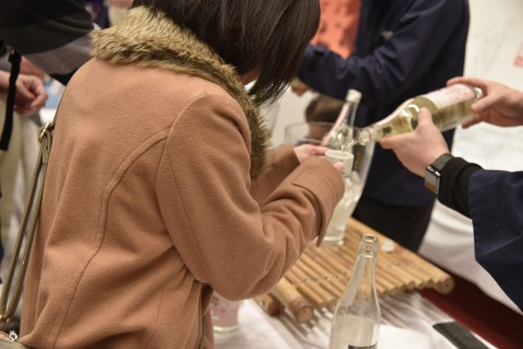 a woman with a sake cup, she is getting her cup filled with sake at a booth