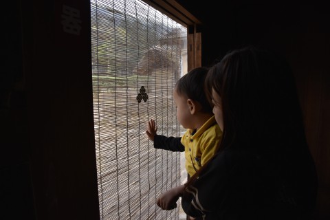 in a restored warrior's residence, Mr. Ugyen Dorji's son and wife are looking at a Japanese fence hanging from the ceiling