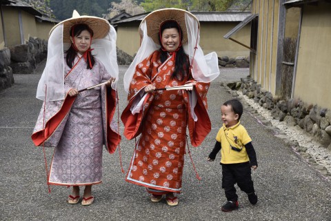 Mr. Ugyen Dorji's sister and wife are smiling wearing kimono, his 2 years old son is ruuning in front of them with his regular clothing